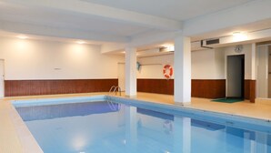 Una piscina al coperto con acqua cristallina, un galleggiante e un orologio appeso al muro.