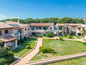 Um complexo residencial moderno com vários edifícios de dois andares, um pátio central e um gramado bem cuidado.