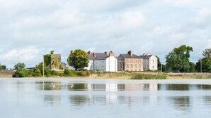 A waterfront property with multiple buildings, a bridge, and a calm river. - 4 bed historically significant house sleeping 8 (Clarecastle)