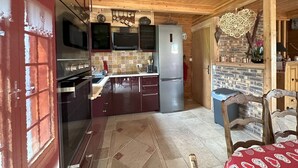 Una cocina compacta con armarios de madera, un refrigerador de acero inoxidable y un salpicadero de azulejos.