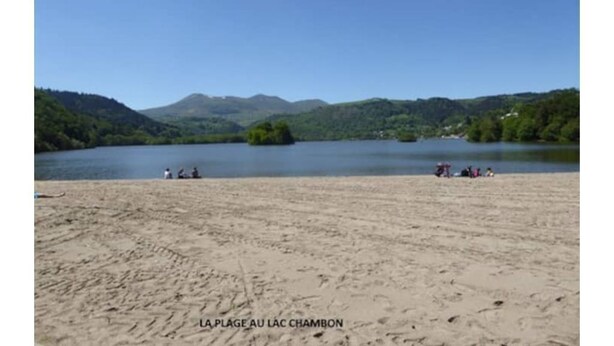Una playa con vistas despejadas a un lago y montañas al fondo.