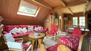 Una cabaña acogedora de madera con un dormitorio en la buhardilla, un conjunto de sofás y un comedor.