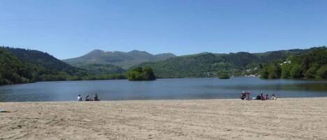 Una playa con vistas despejadas a un lago y montañas al fondo.