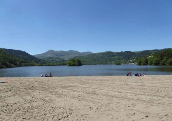 Une plage d’où l’on a une vue dégagée sur un lac et des montagnes en arrière-plan.