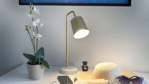 A desk with a potted orchid, a desk lamp, a smartphone, a hat, sunglasses, and a framed picture on the wall. - Hotel Madison (Bellaria-Igea Marina)