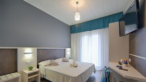 A hotel room with a bed, bedside tables, a desk, a TV, and a window with curtains. - Hotel Madison (Bellaria-Igea Marina)