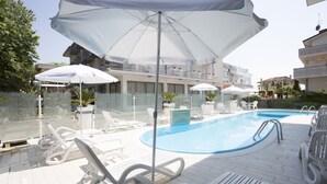 A poolside area with lounge chairs, umbrellas, and a clear blue pool. - Hotel Madison (Bellaria-Igea Marina)