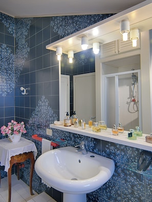 A bathroom with a white sink, a mirror, and a shower. There are toiletries on the counter.