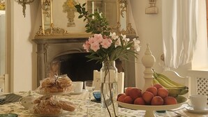 Ein Essbereich mit einer Tischdecke mit Blumenmuster, einem Spiegel mit aufwendiger Goldverzierung und einer Vase mit Blumen.