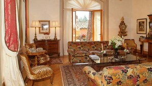 Ein traditionelles Wohnzimmer mit einer Couch, Sesseln, einem Couchtisch und einer Pendelleuchte.