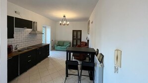 A compact kitchen with a dining area, a green sofa, and a telephone on the wall. - WINE HOUSE ON VESUVIUS (Pollena Trocchia)