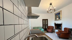 A modern kitchen with a stainless steel sink, a built-in range hood, and a dining area with a table and chairs. - WINE HOUSE ON VESUVIUS (Pollena Trocchia)