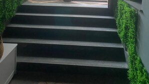 Eine Treppe führt zu einem Außenbereich mit Blick auf ein Gebäude und etwas Grün.