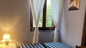 Ein Zimmer mit zwei gestreiften Betten, einem Tisch mit einer Speisekarte und einer Lampe auf einem Nachttisch.