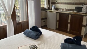 Ein Hotelzimmer mit einem Bett, einem Buch, Handtüchern und einer Küchenzeile mit Wasserkocher und Mikrowelle.