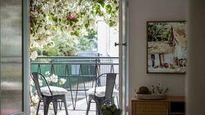Enjoy the serene view from this balcony, featuring a charming seating area with two chairs and a beautiful painting.