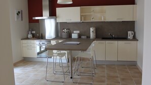 Una cocina moderna con una isla central, taburetes blancos y una lámpara colgante.