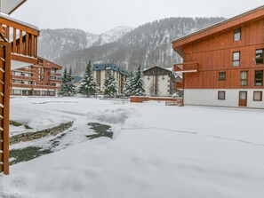 A snow-covered outdoor area with buildings, including a multi-story structure with balconies and a red building with windows. - Modern Apartment with WiFi, Dishwasher, and Balcony – Sleeps 5 in Val-d'Isère (Val-d'Isère)