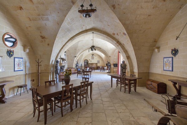Enjoy dining and socializing in this elegant hall with high ceilings, framed artwork, and stone floors.