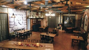 A rustic interior with exposed beams, brick walls, and a stone fireplace. Tables and chairs are arranged for dining. - Chalet Mestia (Mestia)