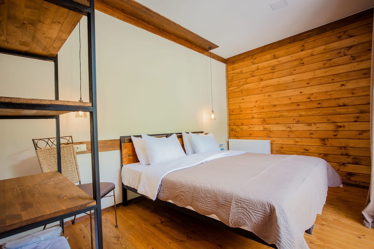 A room with a wooden bed, a wooden table, and a chair.