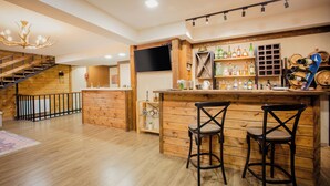 A bar area with wooden furniture, a TV, and shelves with bottles. - Chalet Mestia (Mestia)