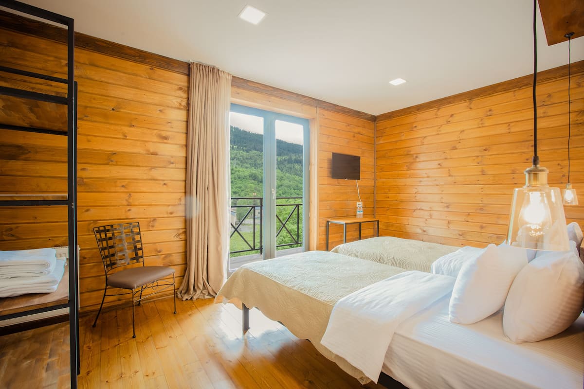 A wooden-paneled room with a bed, a chair, and a TV on a wall.