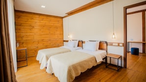 A room with two beds, wooden walls, a small table, and a hanging light fixture. - Chalet Mestia (Mestia)