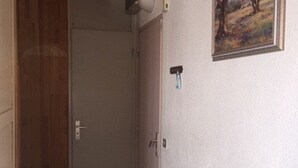 A narrow hallway with a wooden door on the left and a white door on the right. There is a small painting on the wall above the white door. - Arette: Large studio for 6 near slopes, parking, dishwasher (Arette)