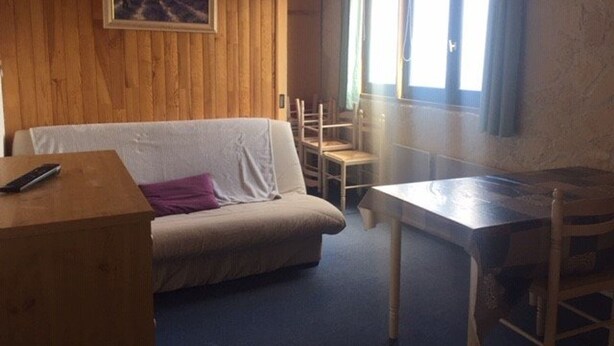 A cozy room with a wooden wall, a sofa, a table, and chairs. - Arette: Large studio for 6 near slopes, parking, dishwasher (Arette)