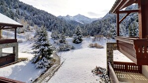 A snow-covered landscape with a wooden building featuring a balcony and stone walls. - Charming 2-room cabin in quiet residence - WiFi included (Méribel)