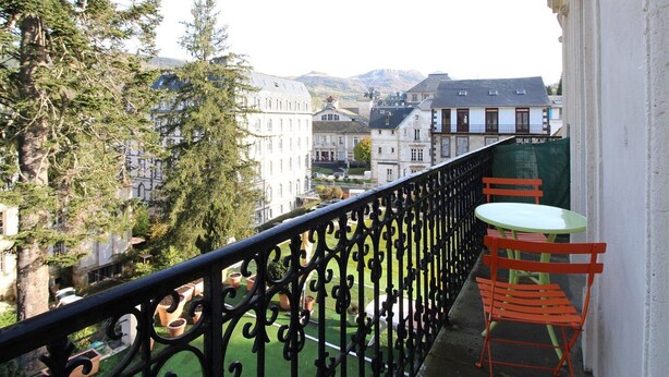 Un balcon donnant sur des immeubles et des arbres.