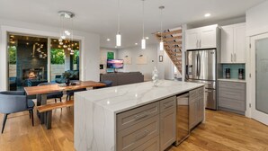 Une cuisine moderne dotée d’un îlot en marbre, d’appareils électroménagers en acier inoxydable et d’un escalier en bois.