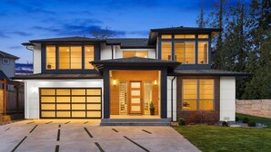 Une maison moderne à deux étages, dotée d’un garage, de grandes fenêtres et d’une pelouse bien entretenue.