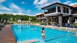 A swimming pool with lounge chairs and umbrellas, a two-story building with balconies, and a clear blue sky. - Boutique Complex Trakiets (Kaloyanovo)