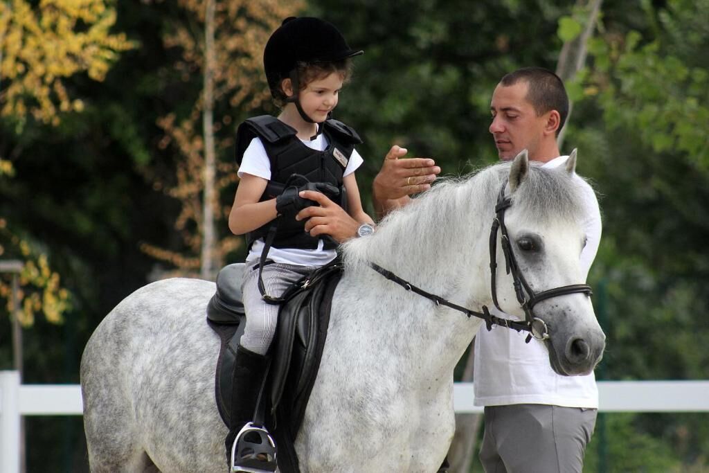 A child riding a horse with an adult.
