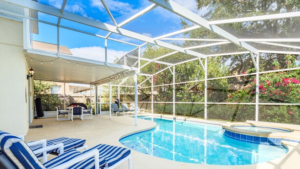 Une piscine extérieure couverte, dotée de chaises longues et d’un espace patio.