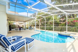 A covered outdoor swimming pool with lounge chairs and a patio area. - ⭐⭐ Spacious & Modern 4 bed Family Home | Only 10 minutes to Disney! ⭐⭐ (Davenport)