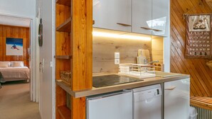 A compact kitchen with wooden cabinetry, a built-in dishwasher, and a small countertop. - Spacious apartment with WiFi at the foot of the slopes - La Daille (Val-d'Isère)