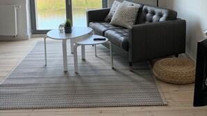 Una sala de estar moderna con un sofá de cuero, una mesa de centro redonda y un ventanal con vistas a un campo.