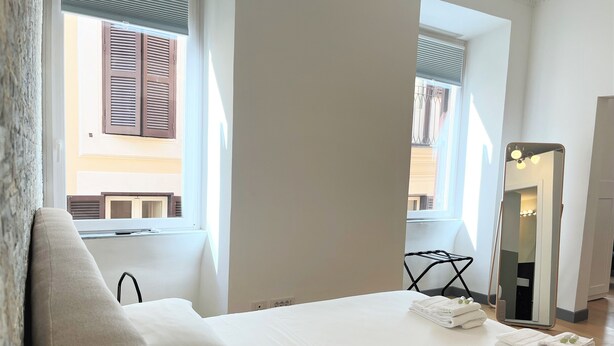 A hotel room with a bed, a large mirror, and a window with shutters. - APARTMENT 3 PANTHEON (Roma)