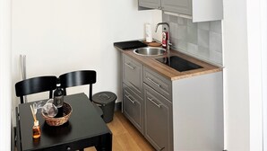 A compact kitchen with grey cabinets, a black countertop, and a wooden floor. - APARTMENT 3 PANTHEON (Roma)