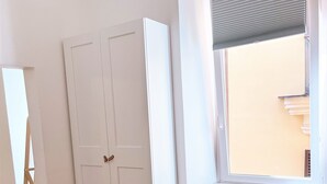 A room with a white wardrobe, a black chair, and a window with blinds. - APARTMENT 3 PANTHEON (Roma)