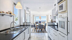 A modern kitchen with a central island, built-in oven, and a dining area with a view.