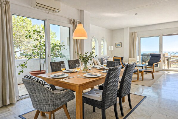 A dining area with a wooden table, wicker chairs, and a hanging pendant light.