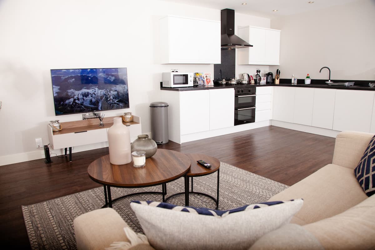 Un salon moderne avec un téléviseur à écran plat, une table basse en bois et un canapé agrémenté de coussins décoratifs.