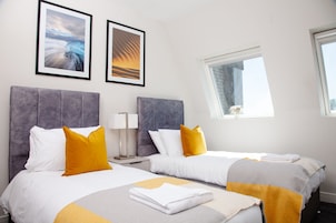 Habitación de hotel con dos camas, una ventana y dos cuadros en la pared.