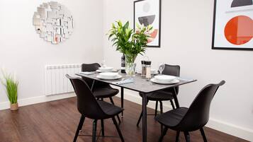 A dining area with a rectangular table, black chairs, white plates, and a vase with flowers.