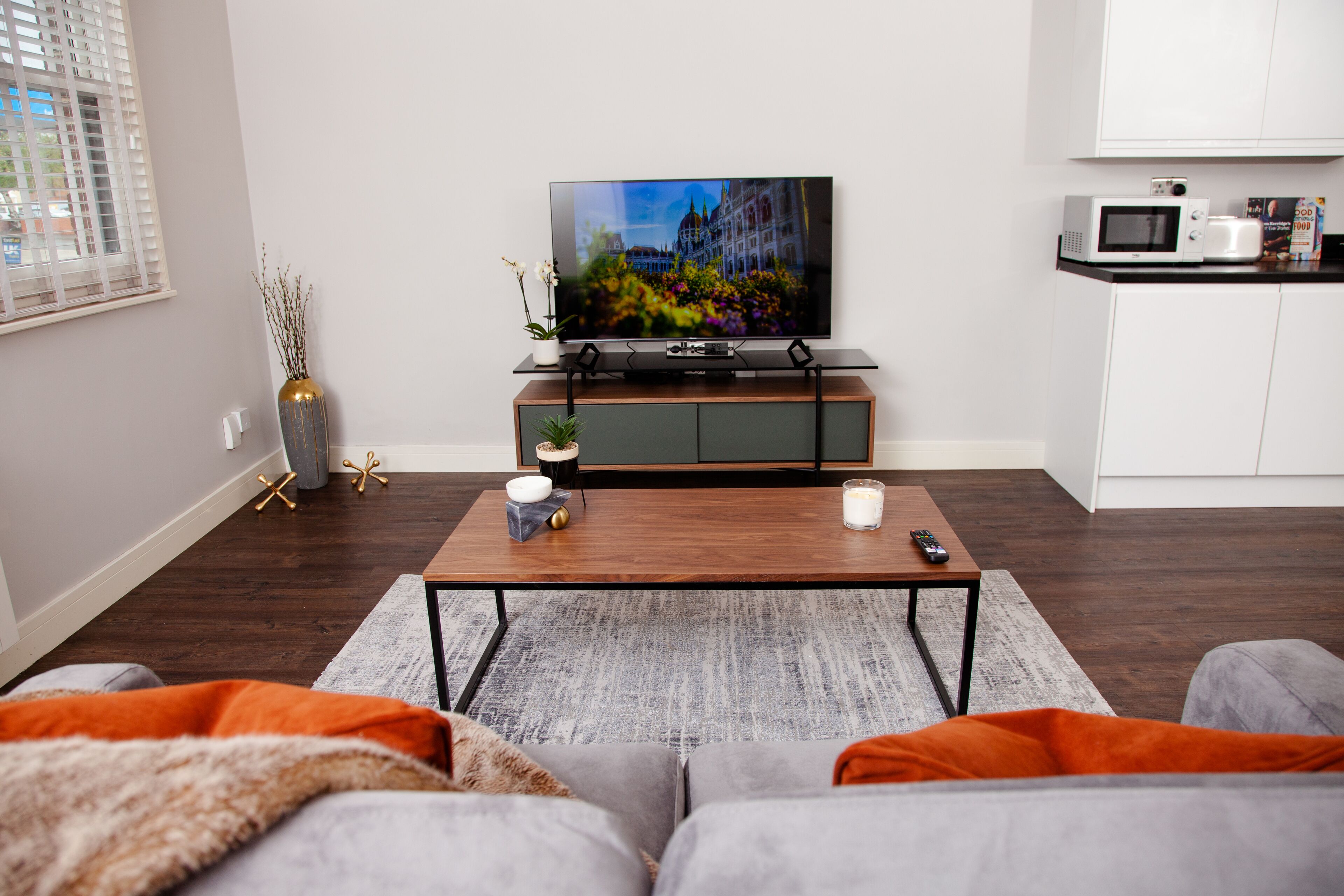 Ett modernt vardagsrum med en platt-TV, ett soffbord och en soffa.