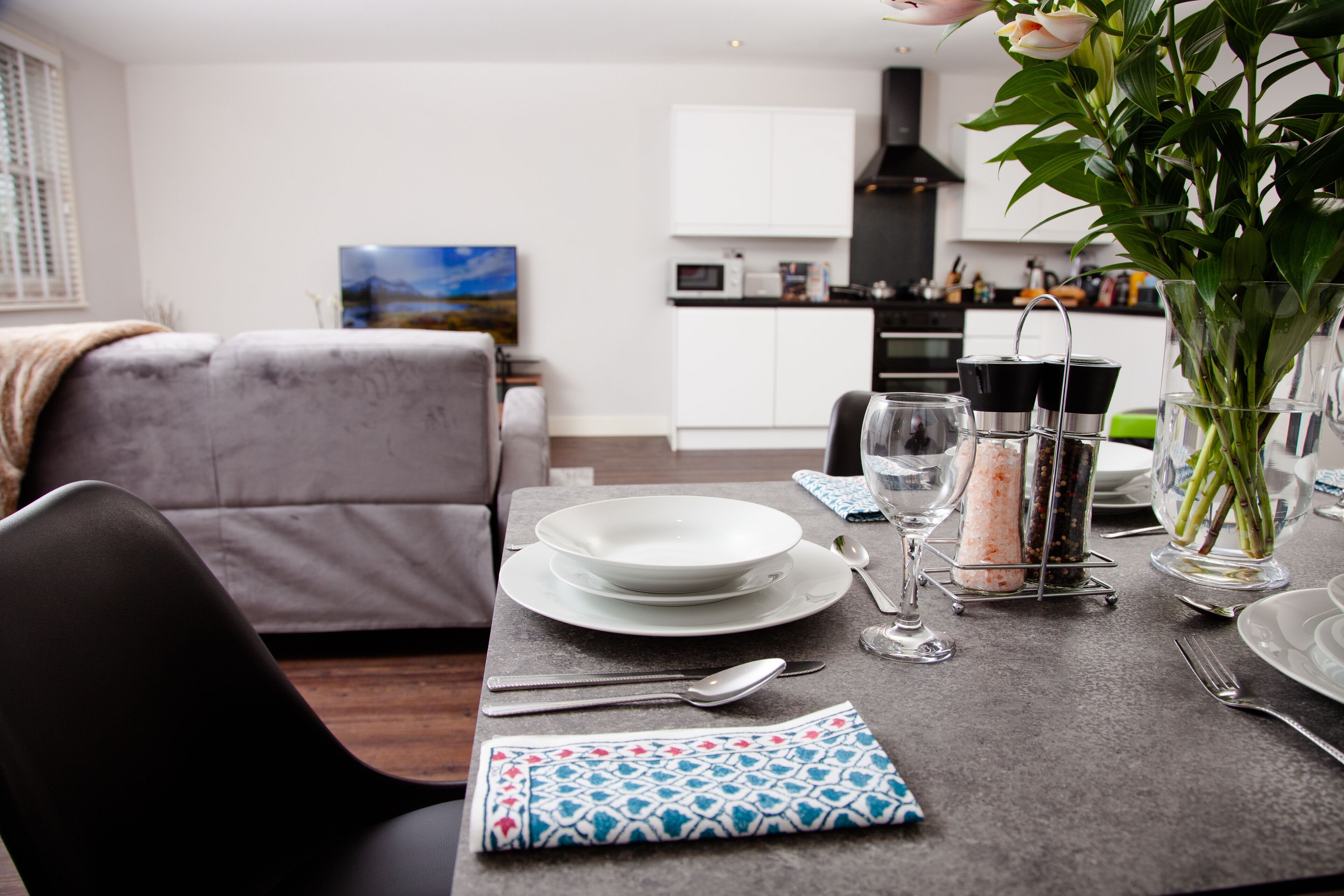 A dining table set with plates, cutlery, and a salt and pepper shaker.